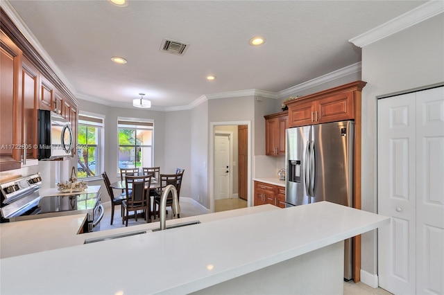1632 NE Winterberry Ln, Weston, FL 33327 - kitchen featuring light countertops, appliances with stainless steel finishes, brown cabinetry, ornamental molding, and a peninsula