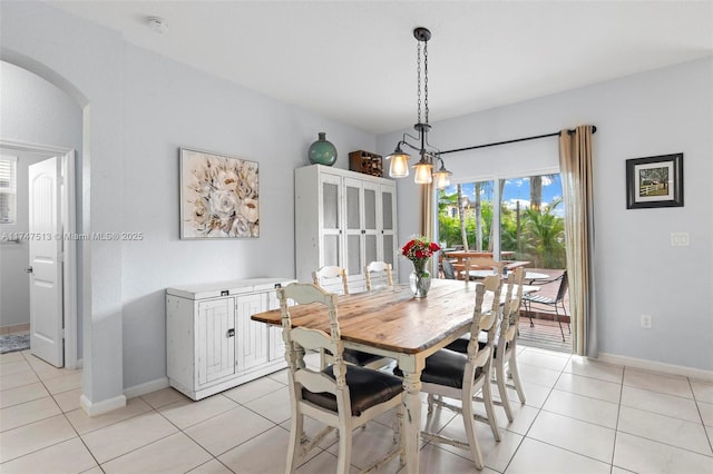 dining space featuring light tile patterned flooring, arched walkways, and baseboards
