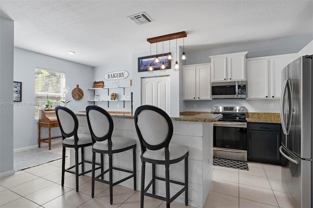 kitchen with white cabinetry, a breakfast bar, stainless steel appliances, light tile patterned floors, and visible vents