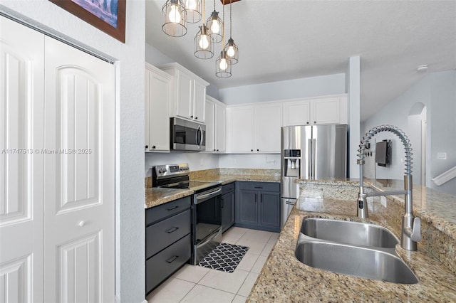 kitchen featuring stainless steel appliances, light tile patterned flooring, a sink, pendant lighting, and white cabinets