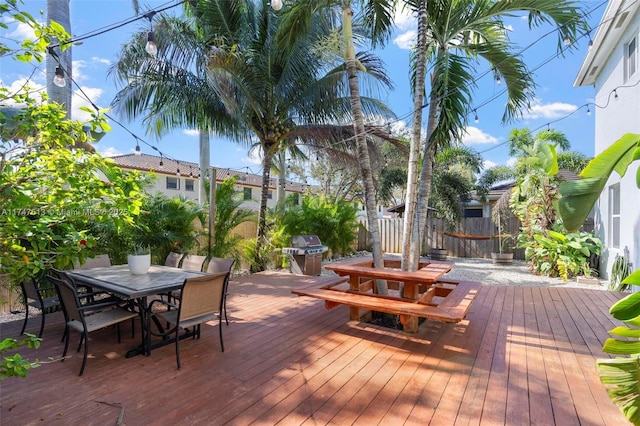 wooden deck featuring outdoor dining area, area for grilling, and fence