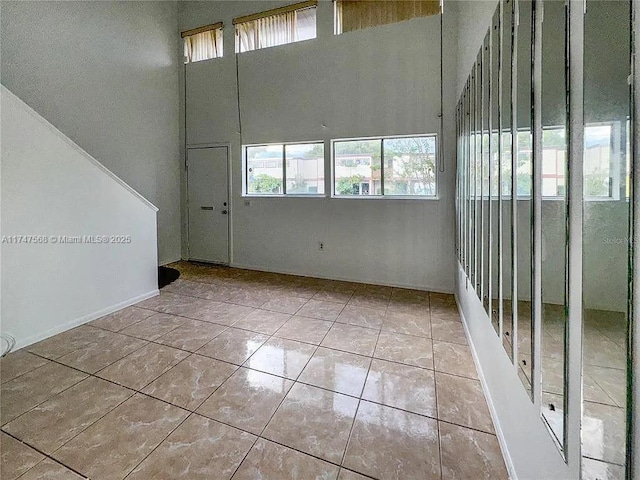 unfurnished room featuring light tile patterned floors and a towering ceiling