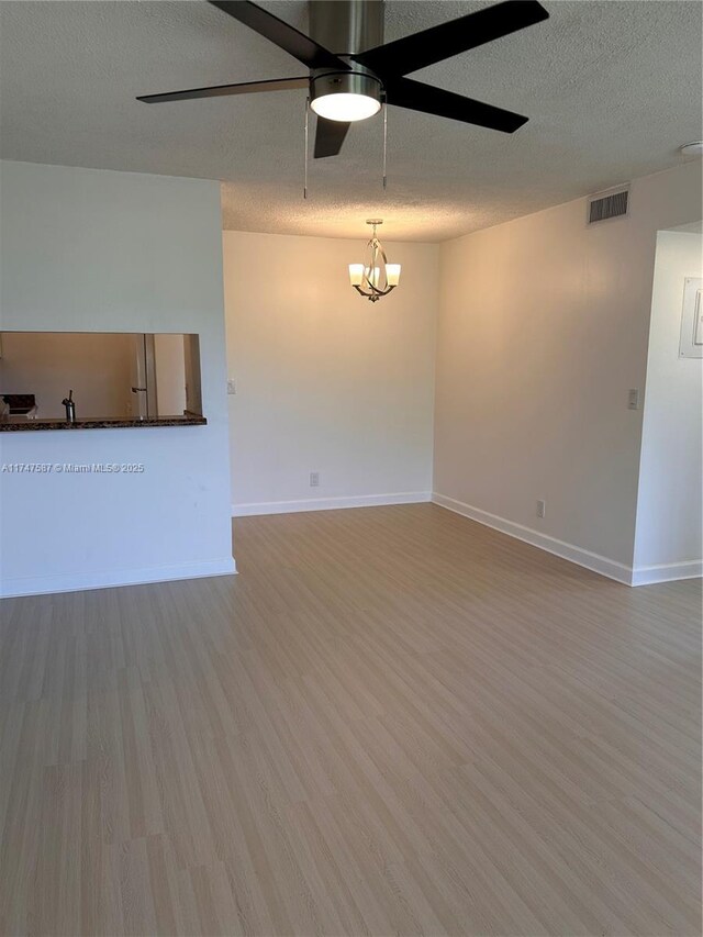 unfurnished living room with hardwood / wood-style floors, sink, ceiling fan with notable chandelier, and a textured ceiling