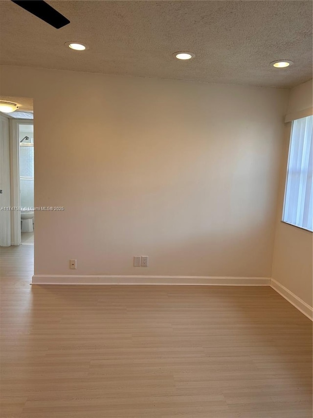 unfurnished room featuring light wood-type flooring and a textured ceiling