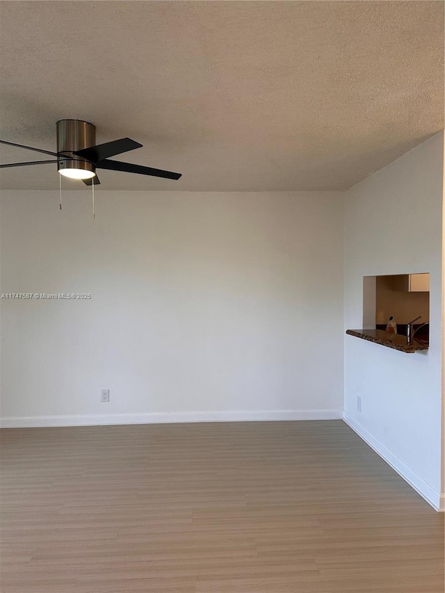 empty room featuring ceiling fan, a textured ceiling, and hardwood / wood-style floors
