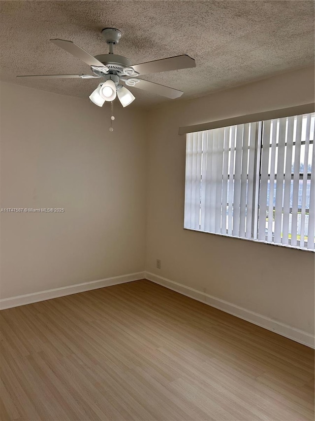 empty room with ceiling fan, light hardwood / wood-style floors, a textured ceiling, and a healthy amount of sunlight