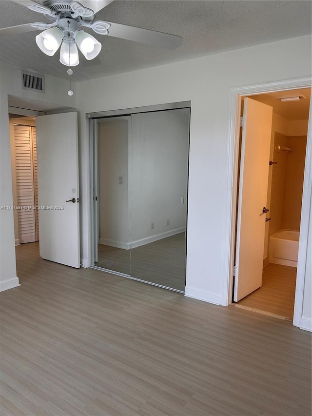 unfurnished bedroom featuring light wood-type flooring, a closet, a textured ceiling, and ceiling fan