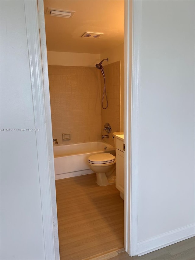 full bathroom featuring toilet, wood-type flooring, vanity, and tiled shower / bath
