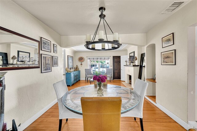 dining room with baseboards, a fireplace, visible vents, and light wood-style floors