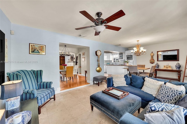 living area with ceiling fan with notable chandelier, light tile patterned floors, visible vents, and baseboards