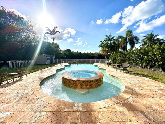 view of swimming pool featuring a patio, an in ground hot tub, and a storage shed