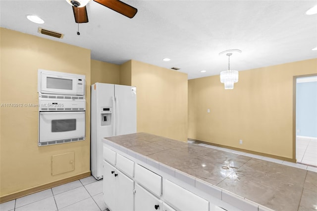 kitchen with white appliances, white cabinets, tile counters, pendant lighting, and light tile patterned floors