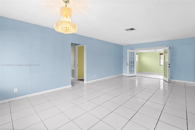 spare room featuring light tile patterned flooring, french doors, a textured ceiling, and a notable chandelier