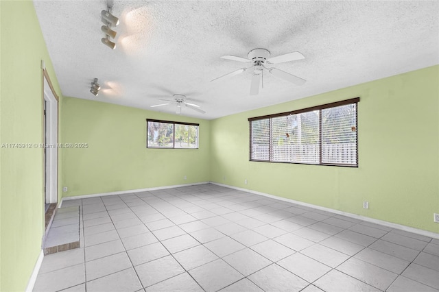 tiled spare room with track lighting, ceiling fan, and a textured ceiling