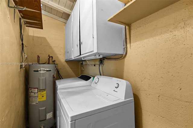 clothes washing area featuring washing machine and dryer, electric water heater, and cabinets