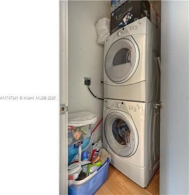 laundry room featuring wood-type flooring and stacked washing maching and dryer