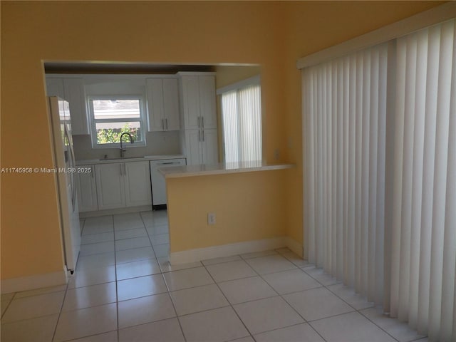 kitchen featuring sink, kitchen peninsula, white appliances, and white cabinets