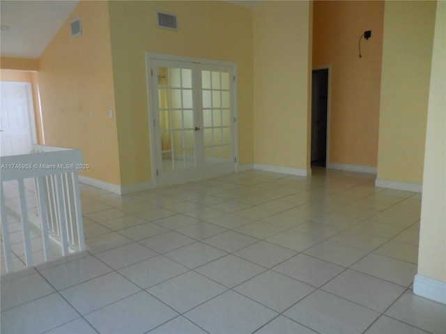 tiled empty room featuring high vaulted ceiling and french doors