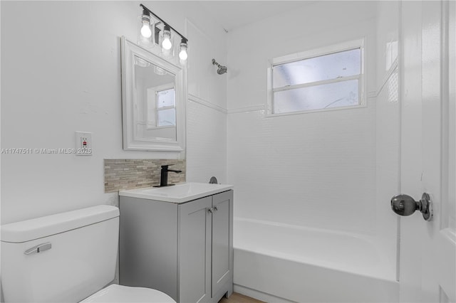 full bathroom featuring toilet, vanity, tiled shower / bath, and decorative backsplash