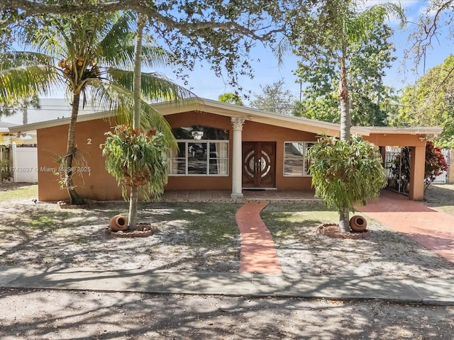 view of front facade featuring a carport, stucco siding, and decorative driveway