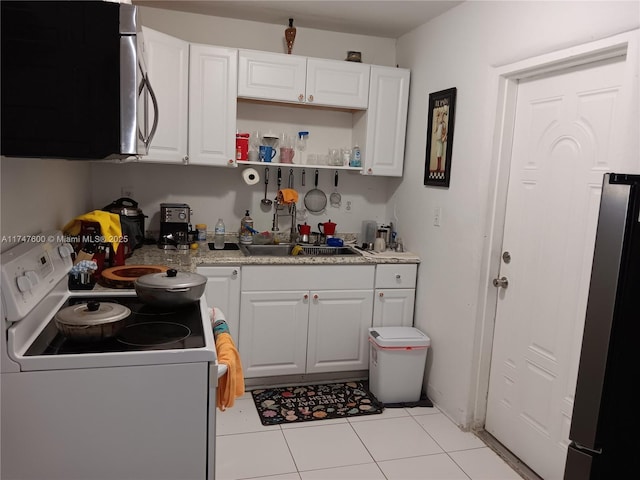 kitchen with stainless steel appliances, sink, light stone counters, light tile patterned floors, and white cabinets