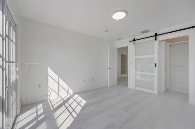 unfurnished room with light hardwood / wood-style floors and a barn door