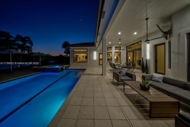 pool at dusk with a patio, an in ground hot tub, and an outdoor hangout area