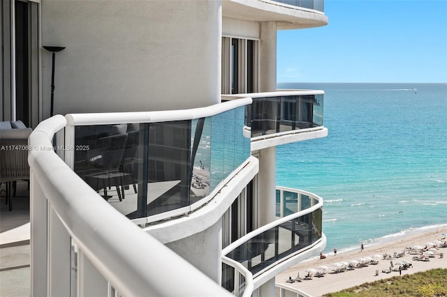 balcony with a water view and a view of the beach