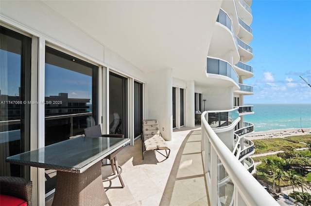 balcony with a water view and a view of the beach