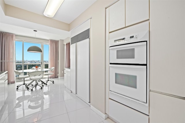 kitchen featuring white double oven, light tile patterned floors, white cabinets, and pendant lighting