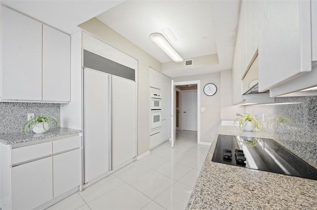 9601 Collins Ave Unit 1208, Bal Harbour, FL 33154 - kitchen with paneled refrigerator, black electric stovetop, decorative backsplash, and white cabinetry