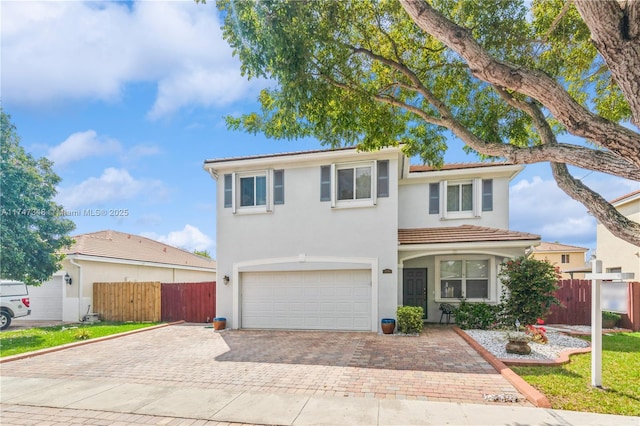 view of front of home with a garage, decorative driveway, fence, and stucco siding