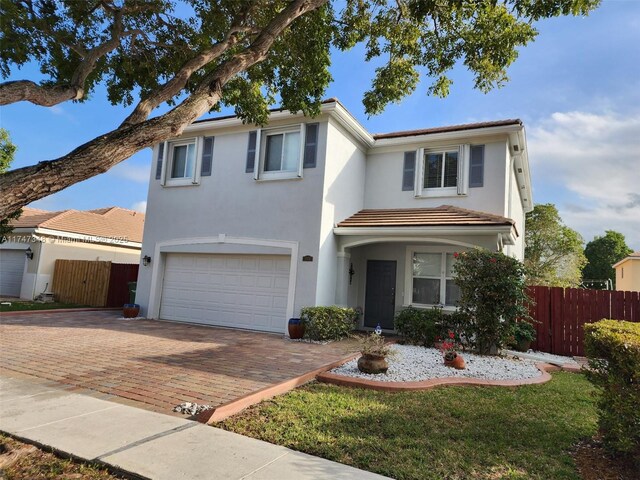 traditional-style home with stucco siding, a garage, fence, and decorative driveway