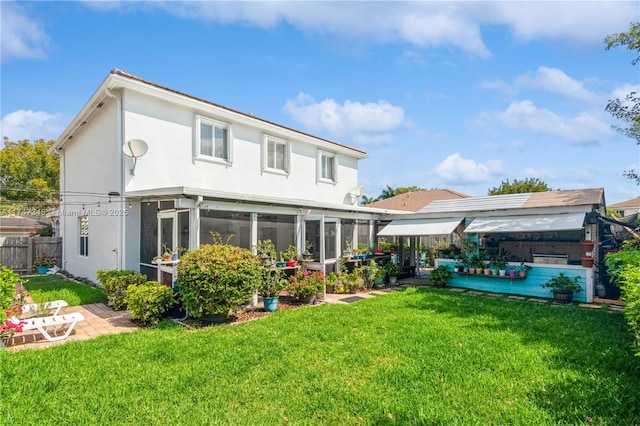 back of house featuring a patio, a sunroom, fence, a yard, and stucco siding