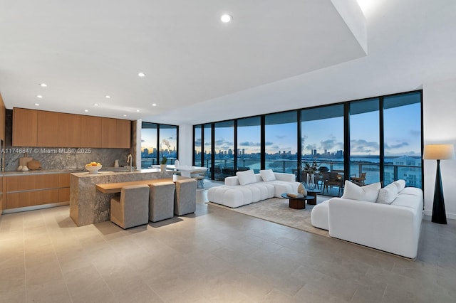 kitchen featuring floor to ceiling windows, a center island, a water view, sink, and decorative backsplash