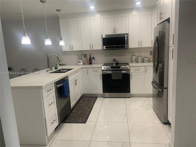 kitchen with marble finish floor, light countertops, appliances with stainless steel finishes, a sink, and a peninsula