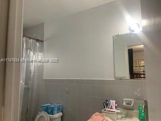 full bath with a shower with curtain and tile walls