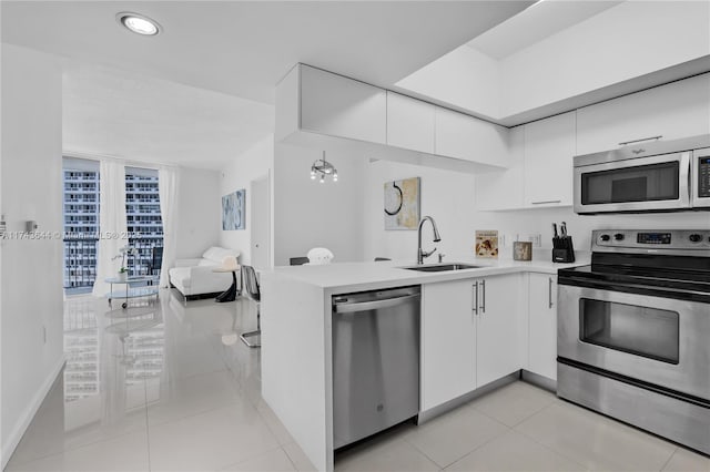 kitchen featuring a sink, appliances with stainless steel finishes, white cabinets, light countertops, and light tile patterned floors