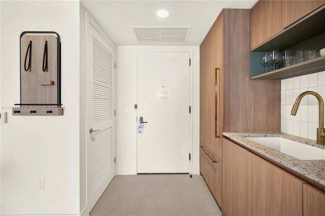 entryway with a sink, visible vents, and light tile patterned floors