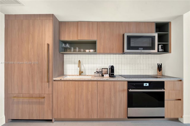 kitchen featuring stainless steel microwave, open shelves, oven, black electric stovetop, and a sink