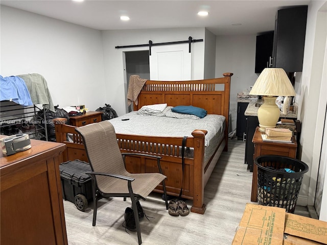 bedroom with a barn door and light hardwood / wood-style flooring