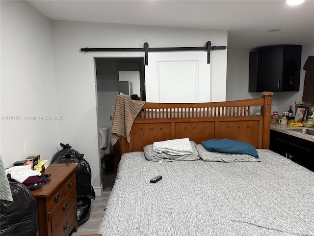 bedroom featuring light hardwood / wood-style flooring and a barn door