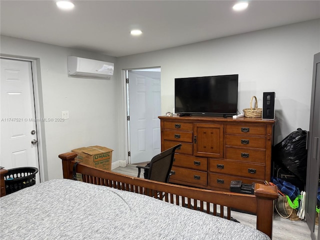 bedroom with a wall mounted air conditioner and light hardwood / wood-style flooring