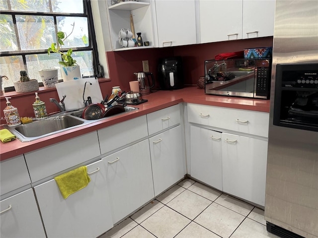 kitchen with light tile patterned floors, sink, stainless steel appliances, and white cabinets