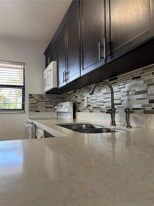 kitchen featuring sink, white appliances, dark brown cabinetry, and decorative backsplash