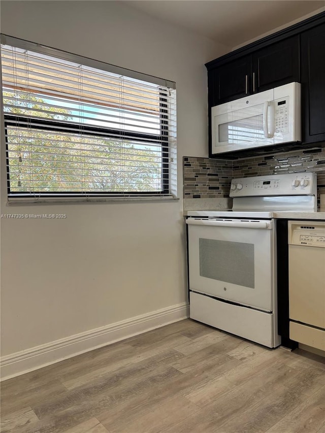 kitchen featuring light wood-type flooring, white appliances, and tasteful backsplash