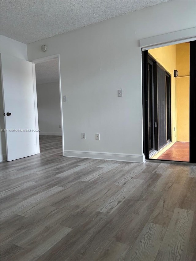 unfurnished room with a textured ceiling and hardwood / wood-style floors