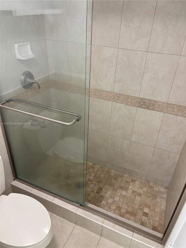 bathroom with a shower with shower door and toilet