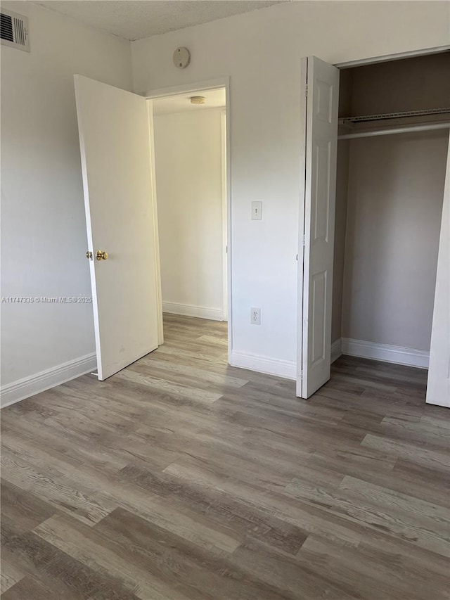 unfurnished bedroom featuring a closet and hardwood / wood-style floors