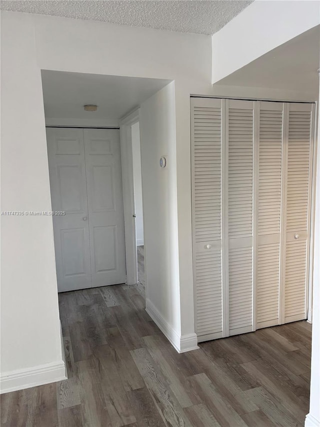 hallway with dark wood-type flooring and a textured ceiling